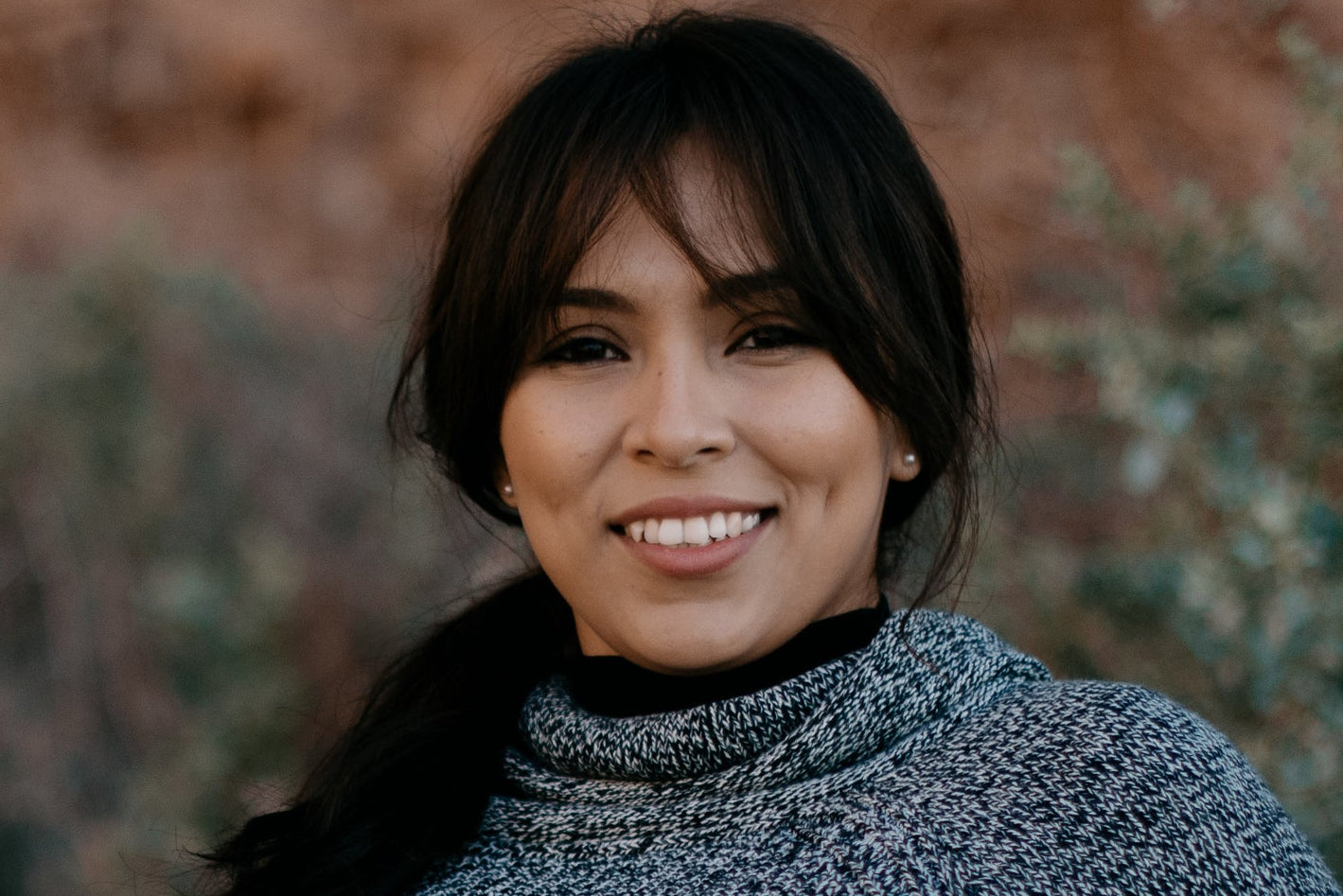 files/woman-in-a-sweater-smiles-as-she-leans-against-a-fence.jpg